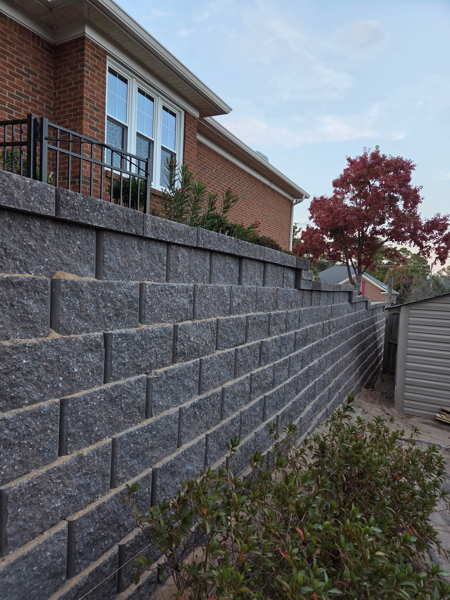 Engineered block retaining wall for grade management and erosion control