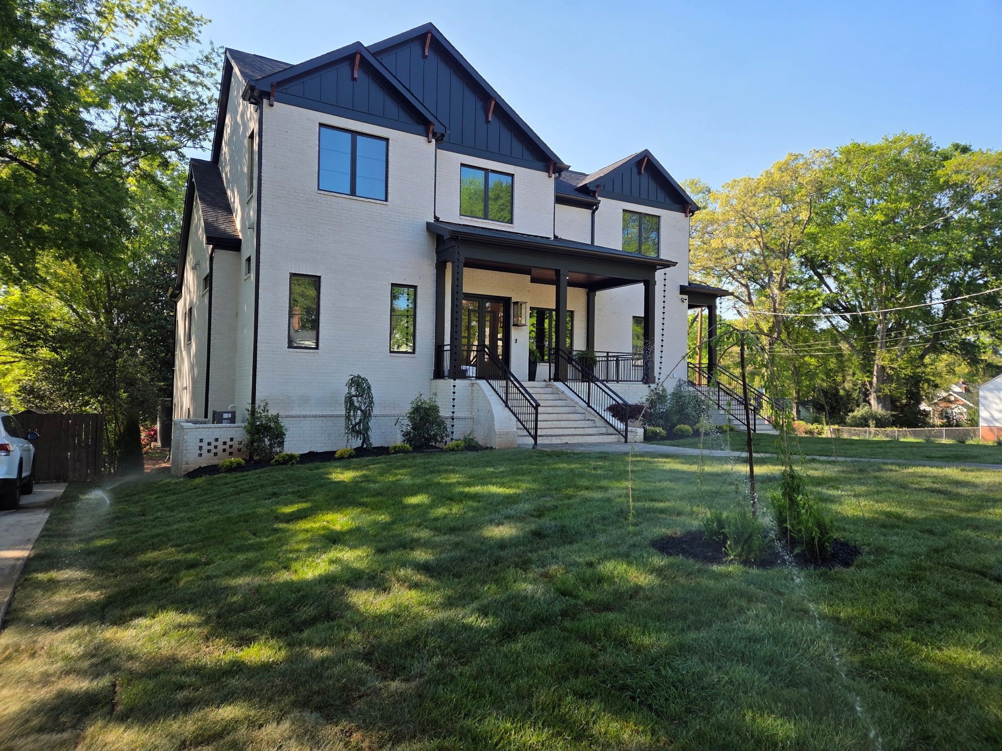 Professional lawn maintenance with sprinklers on a large residential property